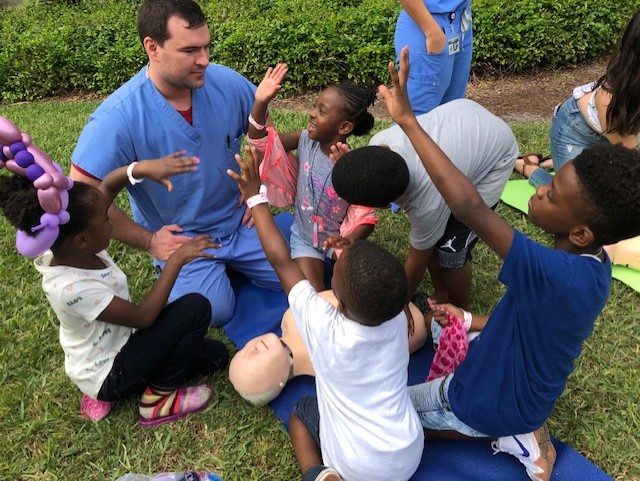 Medical Student teaching CPR to children at Community Fest - NSU